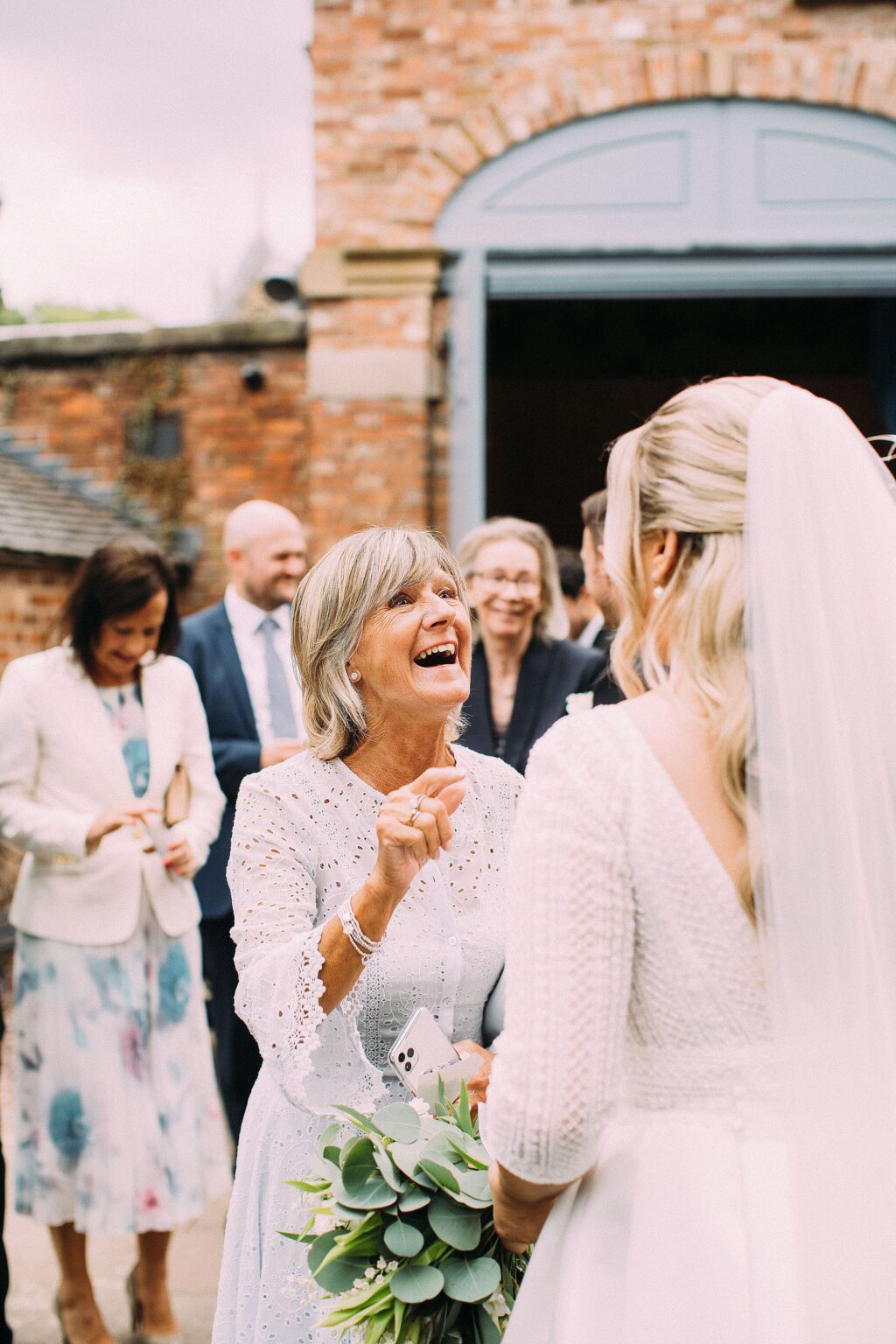 Mum laughing as she greets the bride