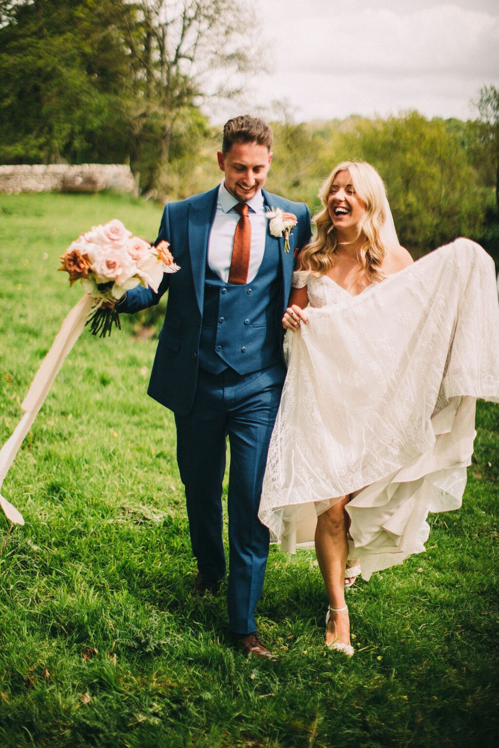 Couple laughing as they walk across a field